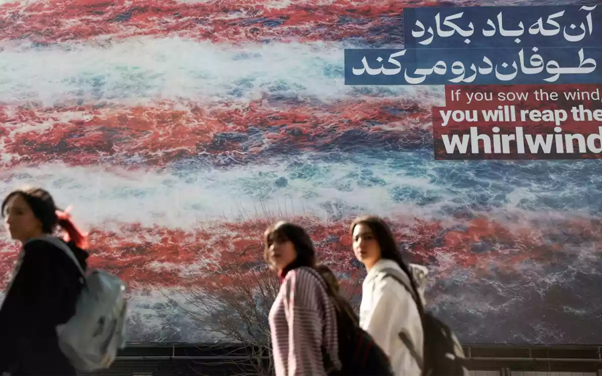 Racing Comilla - Iranian women walk past an anti-U.S. billboard in Tehran, Iran
