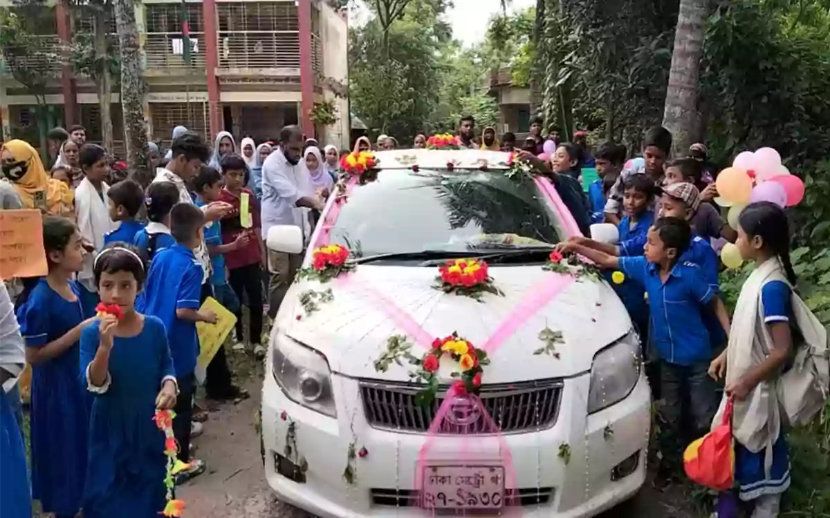 RisingCumilla - Retired headmaster bid farewell in a decorated vehicle amidst a shower of flower petals.